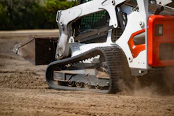 White and orange skid steer loader operating on dirt ground during construction work