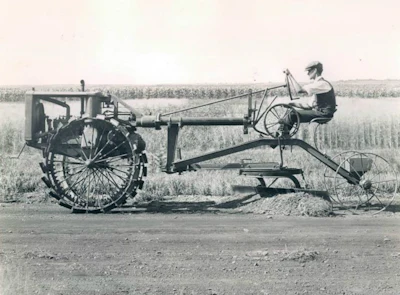 Minneapolis-based Russell Grader Manufacturing Company has been credited with the first self-propelled motor grader. The photo above was taken around 1919 of a Russell Motor Hi-Way Patrol, which combined a tractor engine with the company's pull-behind grader. Caterpillar acquired Russell in 1928 and produced the first motor grader designed as one machine, the Auto Patrol, in 1931.