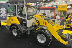 Yellow Wacker Neuson wheel loader with red bucket attachment displayed at indoor trade show booth