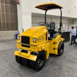 Yellow and black Wacker Neuson vibratory roller compactor on display in an industrial facility with visitors