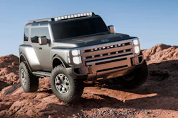 Silver and bronze Land Rover concept SUV parked on rocky desert terrain with clear blue sky