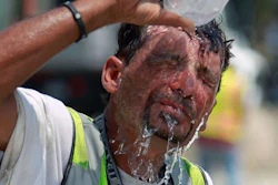 Worker in safety vest pouring water over head for heat relief