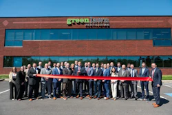 Group of business professionals at Greenlawn ribbon-cutting ceremony in front of brick building