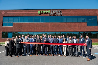 Group of business professionals at Greenlawn ribbon-cutting ceremony in front of brick building