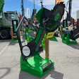 Green and black SENNEBOGEN heavy machinery equipment displayed at outdoor trade show with multiple construction machines in background