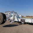 White industrial tire handler truck with large wheel loader attachment in rural field setting