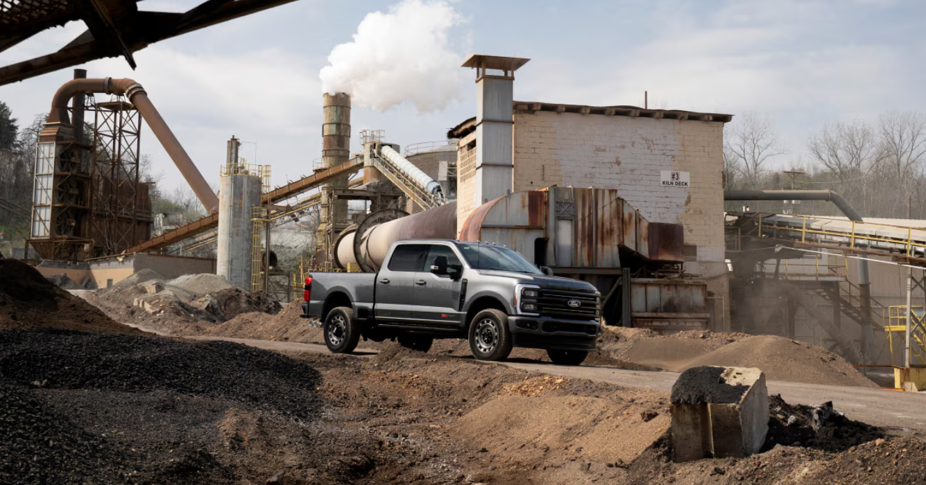 Silver pickup truck parked at industrial aggregate processing facility with conveyor systems and machinery