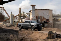 Silver pickup truck parked at industrial aggregate processing facility with conveyor systems and machinery