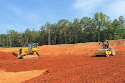 A Bluelight autonomous Cat roller paired with a human-operated dozer on a construction site.