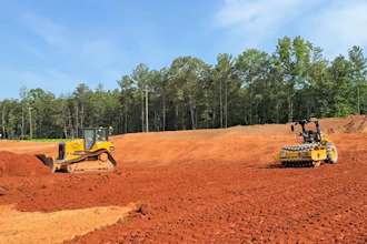 A Bluelight autonomous Cat roller paired with a human-operated dozer on a construction site.