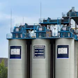 Industrial concrete silos with blue processing equipment and GRH branding under clear sky
