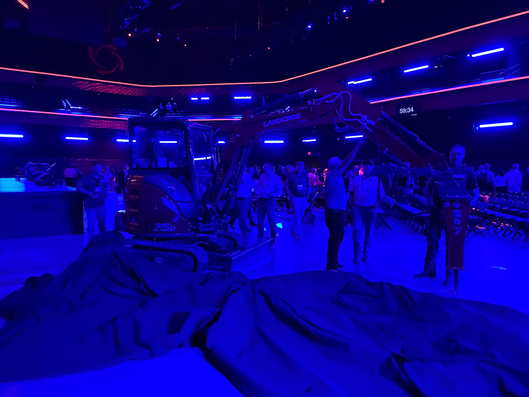 Neon-lit indoor venue with blue and pink lighting, people gathered under illuminated architectural structures