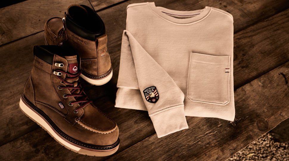 Brown leather boots and cream sweatshirt styled on wooden floor with casual fashion accessories