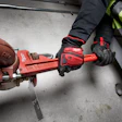 Worker in safety gear using a red Milwaukee pipe wrench on industrial piping