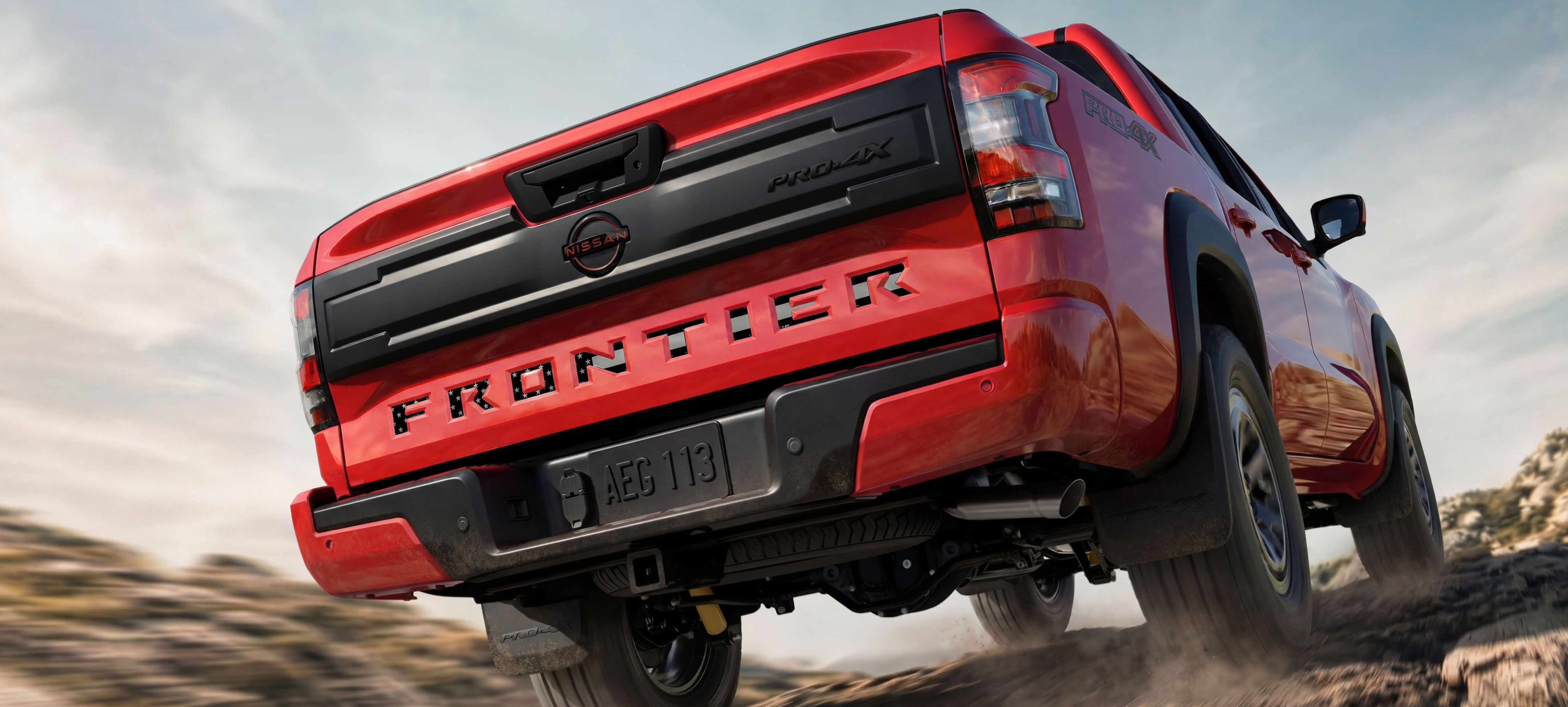 Red Ford Bronco SUV airborne on desert terrain with dust clouds