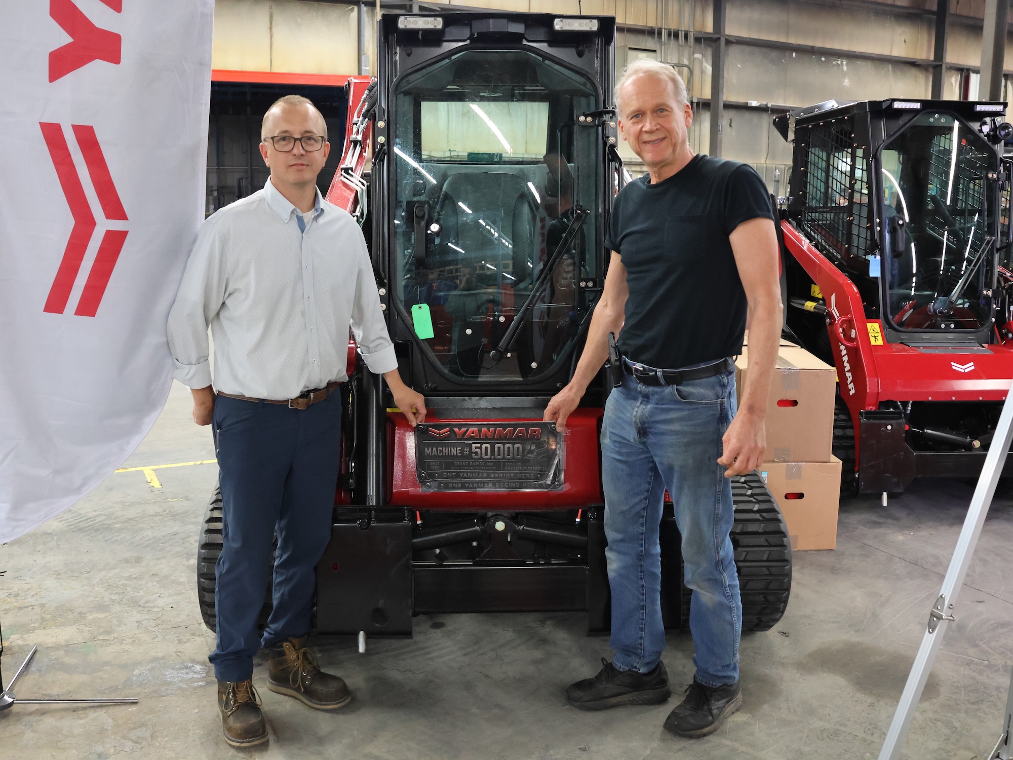 Corey Chick, plant director (left), and Cary Safe, research and development director and legacy employee (right) in front of the TL100, the 50,000th machine off the line.