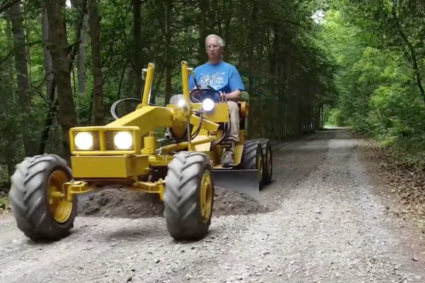 Frank Smith levels the driveway with a mini motor grader he made with a 1972 Cub Cadet lawn tractor.