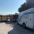 Emergency response vehicles including fire engine and National EMS ambulance parked at roadside during daytime.