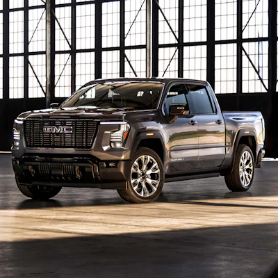 2024 GMC Sierra luxury pickup truck in metallic gray, photographed in industrial warehouse setting