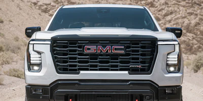 White GMC Sierra pickup truck front view with black grille and LED headlights in desert landscape