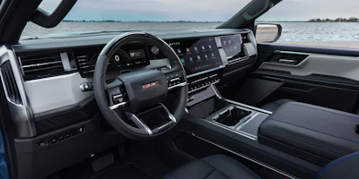 Modern GMC truck interior with digital dashboard, steering wheel, and water view through windshield