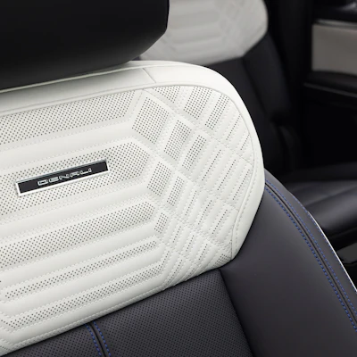 White perforated leather car seat headrest with brand badge and blue stitching detail