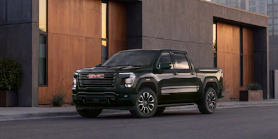 Black GMC Sierra pickup truck parked in front of modern building with copper-toned doors