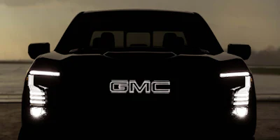 GMC truck front view with illuminated LED headlights and grille badge against neutral background