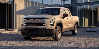 2024 GMC Sierra 1500 crew cab pickup truck in beige parked in modern urban courtyard