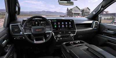 GMC truck interior dashboard with large touchscreen display, steering wheel, and mountain landscape view through windshield