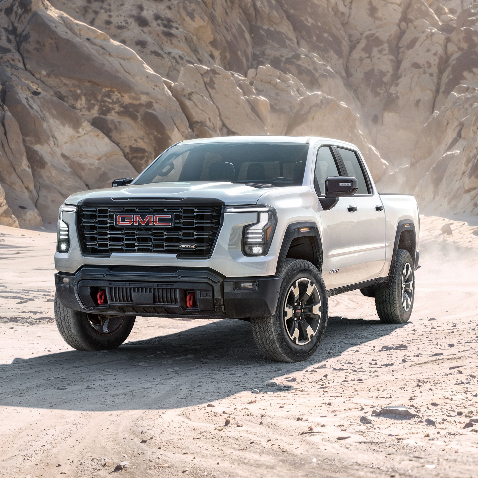 White 2027 GMC Sierra 1500 pickup truck parked on desert terrain with rocky cliff backdrop