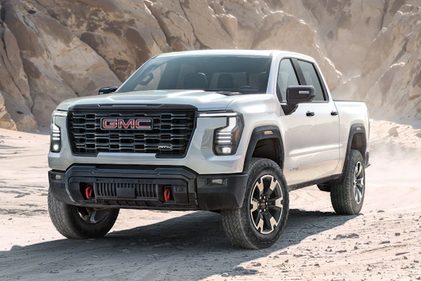 White 2027 GMC Sierra 1500 pickup truck parked on desert terrain with rocky cliff backdrop