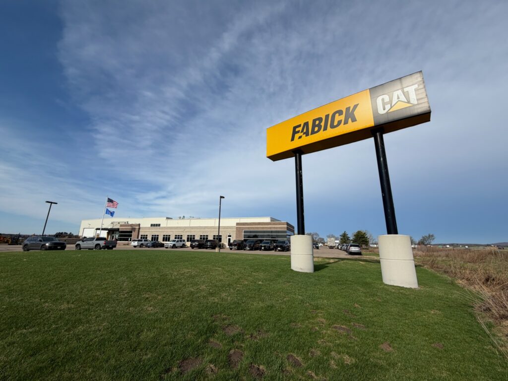 Fabick CAT dealership monument sign on grass with facility building in background under blue sky