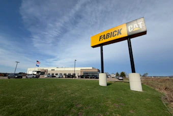 Fabick CAT dealership monument sign on grass with facility building in background under blue sky