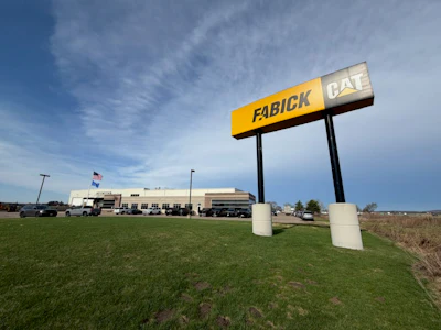 Fabick CAT dealership monument sign on grass with facility building in background under blue sky
