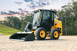 JCB skid steer loader with bucket attachment on gravel surface with trees and cloudy sky