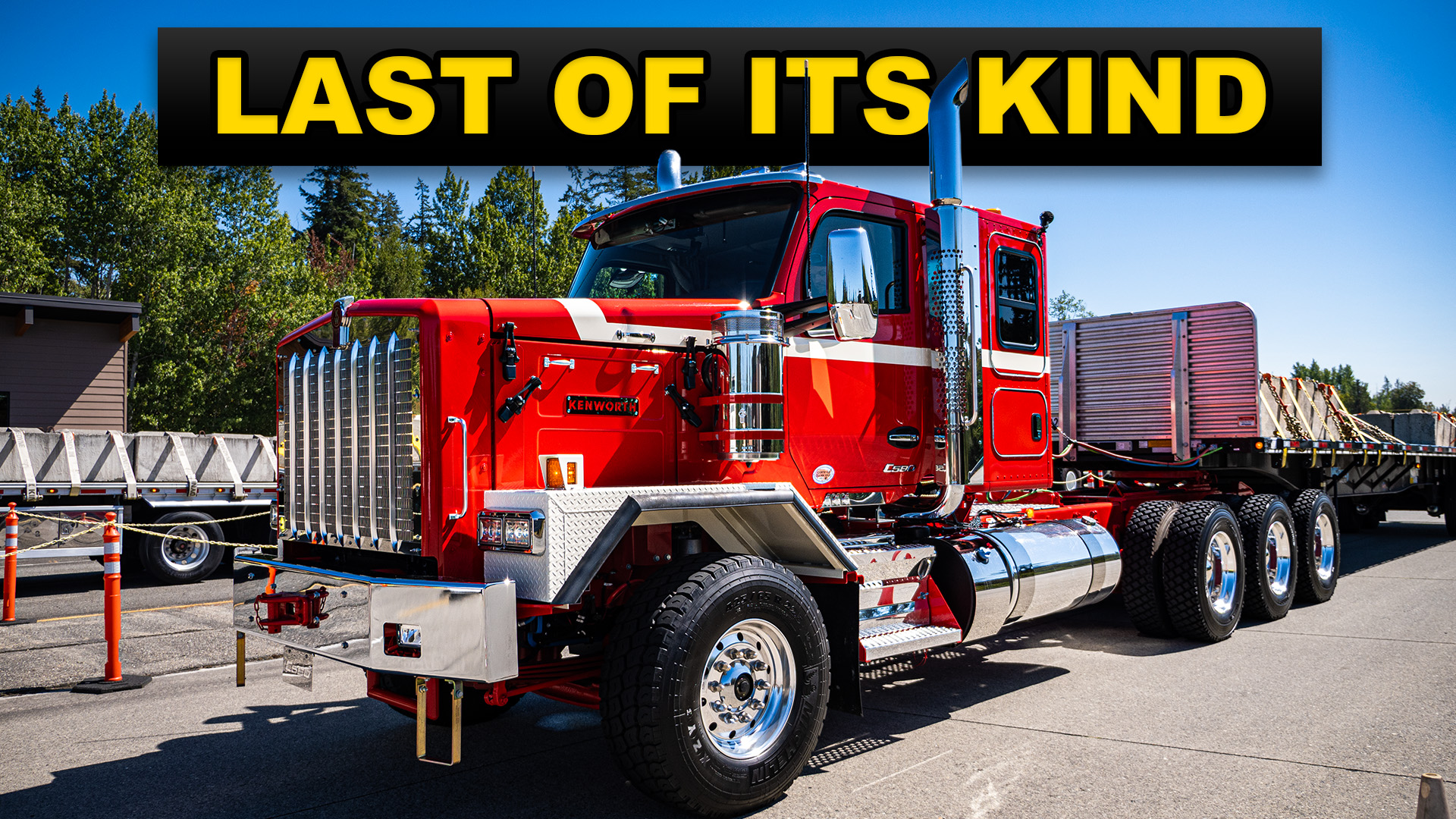 Red Kenworth semi-truck with chrome details parked at a truck stop with other vehicles