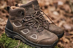 Pair of brown and black hiking boots with laces on rocky, moss-covered ground