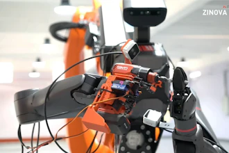 Orange robotic arm with sensors in laboratory setting, ZINOVA Labs branding visible