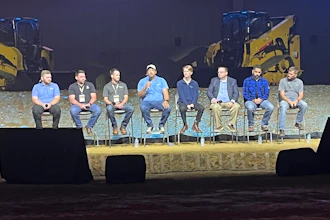 Panel of construction contractors seated on stage during Caterpillar's Tech Days with heavy equipment displayed in the background.