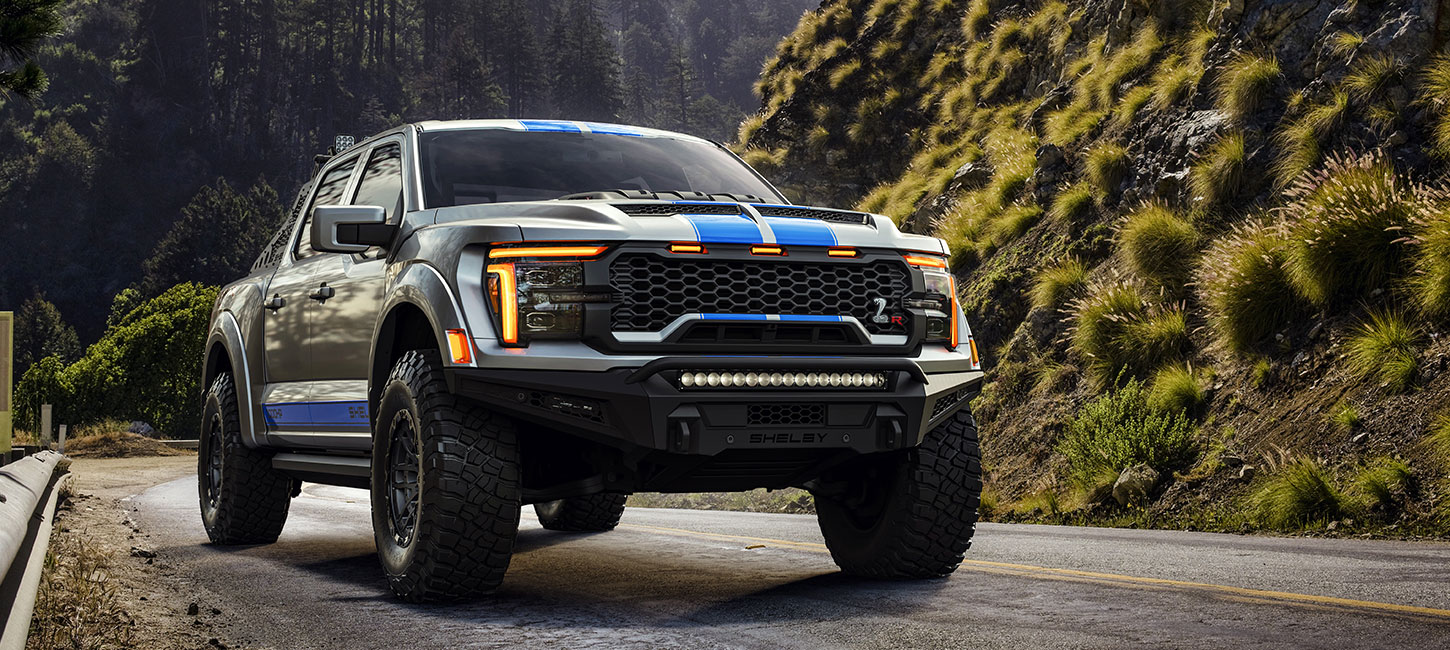 2026 Shelby Ford F-150 Baja Raptor R pickup truck with white and blue racing stripes on forest road
