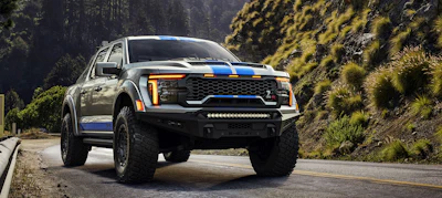 2026 Shelby Ford F-150 Baja Raptor R pickup truck with white and blue racing stripes on forest road