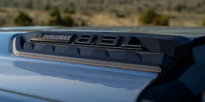 Duramax diesel engine badge mounted on truck hood with desert landscape background