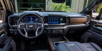 2027 Chevy Silverado HD High Country truck interior dashboard with digital display, leather steering wheel, and wood-tone trim accents