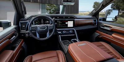 GMC truck luxury interior with brown leather seats, digital dashboard, and wood grain trim accents