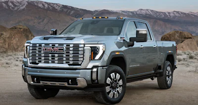 Silver GMC Sierra HD pickup truck parked in desert landscape with snow-capped mountains