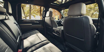 Luxury vehicle interior with black and white leather seats, sunroof, and autumn foliage visible through windows