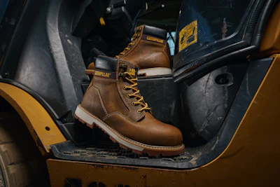 Brown leather Caterpillar work boot with yellow laces displayed in yellow vehicle interior