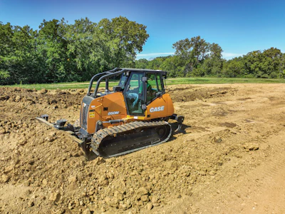 Orange CASE 850M crawler bulldozer operating on dirt terrain with trees in background