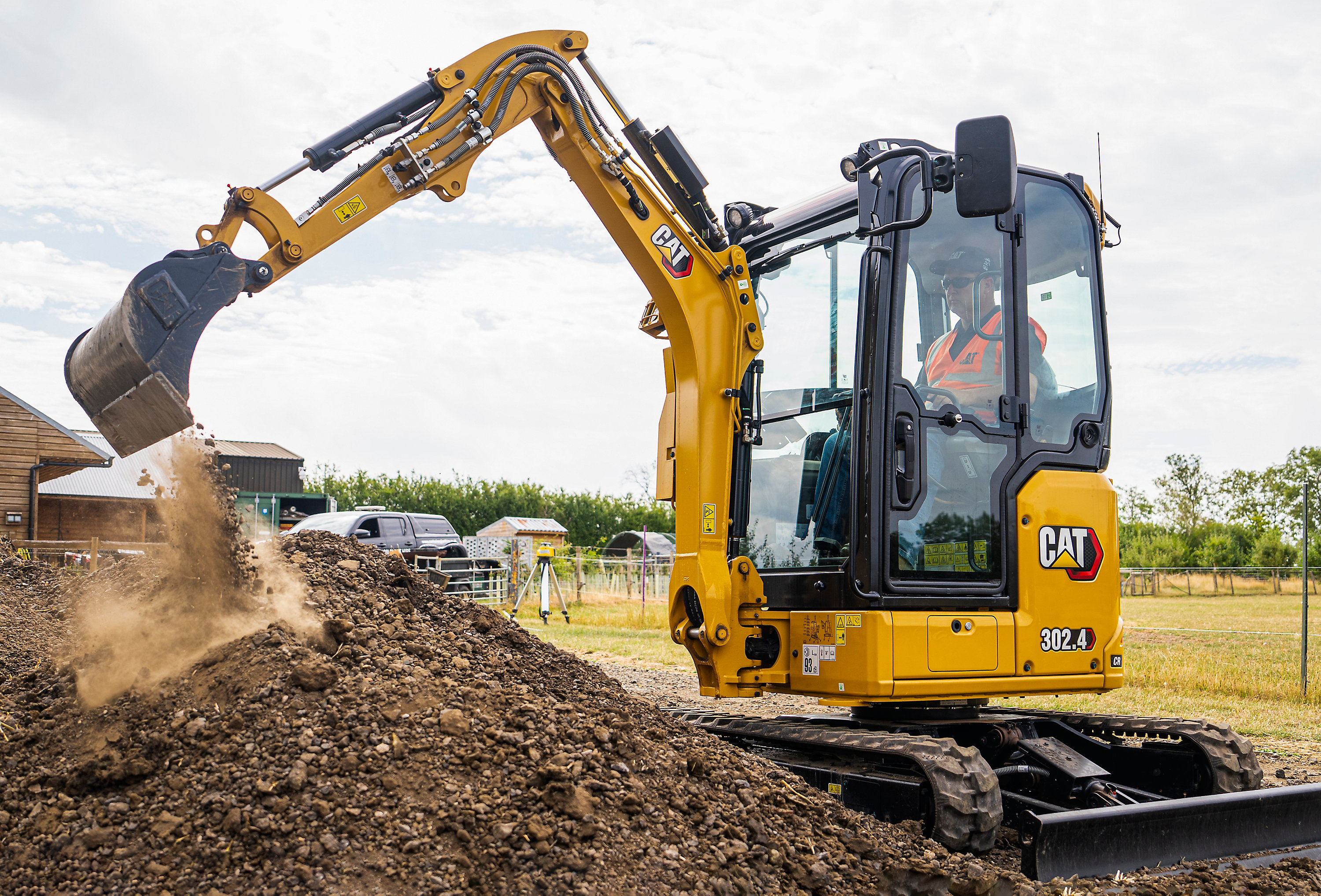 Yellow CAT 382.4 excavator dumping soil at a construction site with operator visible in cab